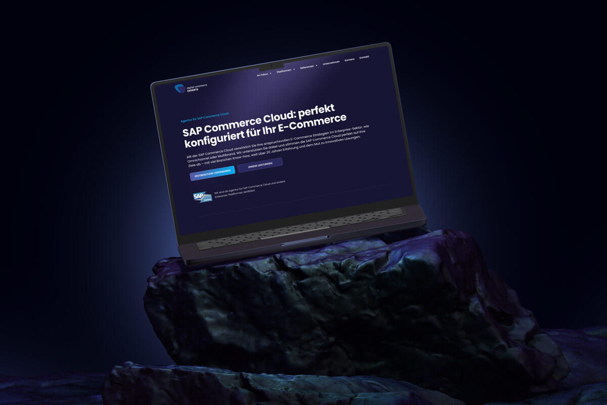 Laptop zeigt SAP Commerce Cloud Seite der Digital Commerce Experts Website – professionell inszeniert auf einem Felsen mit dunklem Hintergrund